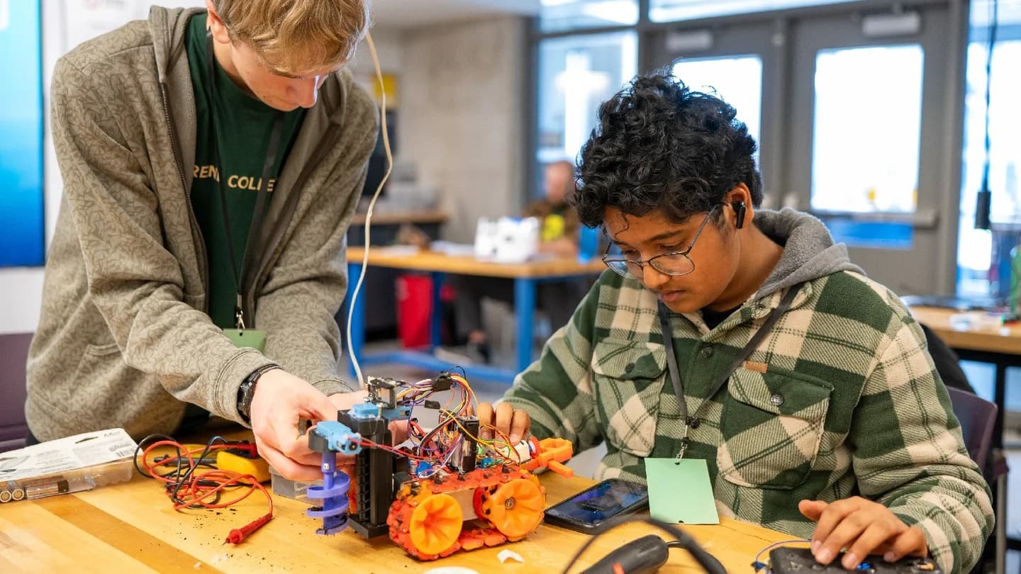 Two students collaborating on a small wheeled robot
